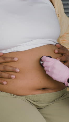 doctor examining pregnant woman with stethoscope