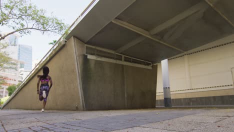 Mujer-Afroamericana-Haciendo-Ejercicio-Al-Aire-Libre-Corriendo-Bajo-El-Puente-En-La-Ciudad