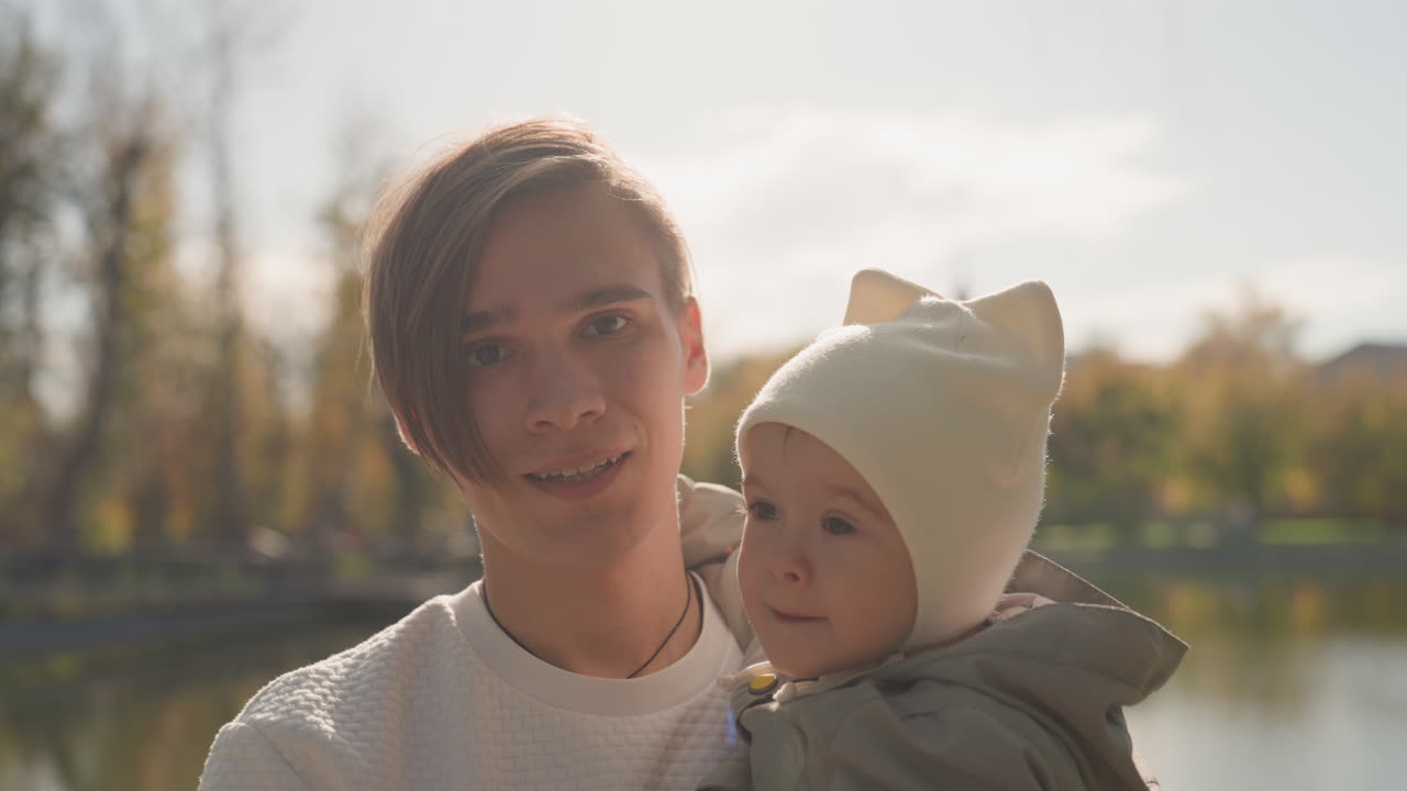 Kærlig far og barn deler glædesfuld udendørs leg. Familiebånd fanget under munter, solrig søudflugt. Ægte scene viser far og baby omfavne glædesfyldte øjeblikke ved solbeskinnet sø