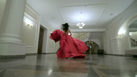woman in a red ballgown in a luxury hallway