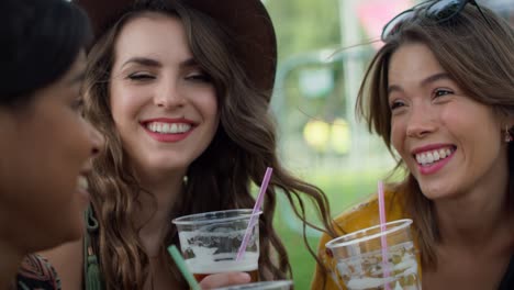 young women sitting on the grass, talking and drinking beers.