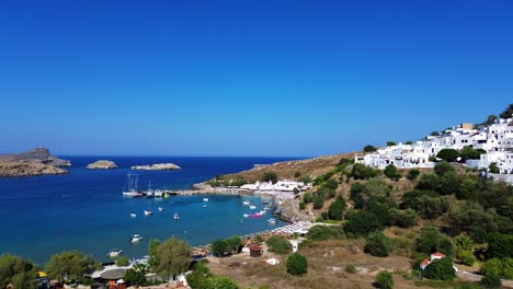 lindos beach and village in rhodes, greece with acropolis of lindos, houses and mediterranean sea during the day filmed with the drone