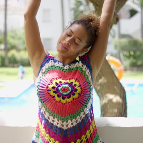 woman in colorful knit top stretching on balcony