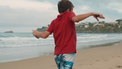 Niño-Activo-Bailando-A-La-Orilla-Del-Mar.-Chico-Despreocupado-Disfrutando-Del-Verano-En-La-Playa-De-Arena.