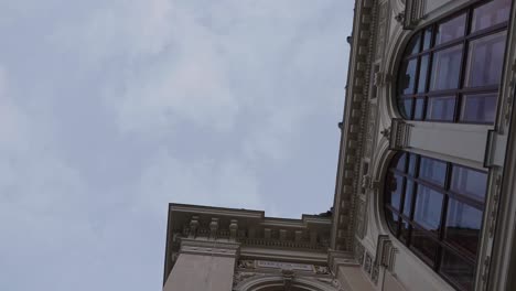 Building-exterior-with-ornaments-and-large-arched-windows-during-overcast-day