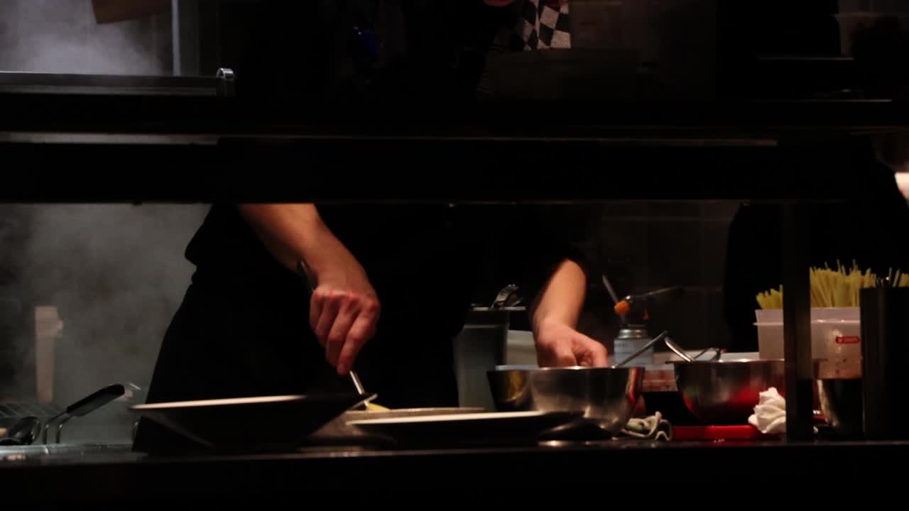 셰프는 스로우 모션으로 전문 레스토랑 주방에서 접시 위의 그에서 파스타를 제공합니다.