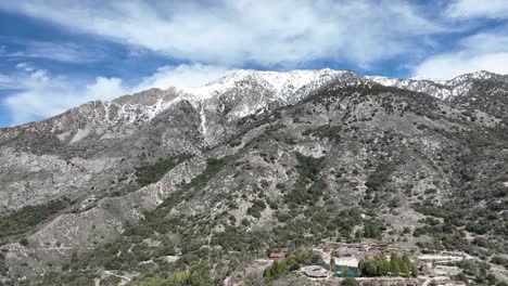 creekside forest home in forest falls southern california with snow covered mountains in the background aerial trucking 60fps