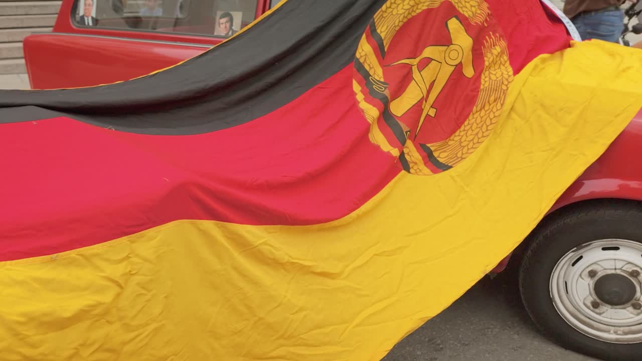 German Democratic Republic flag draped across Eastern European cars