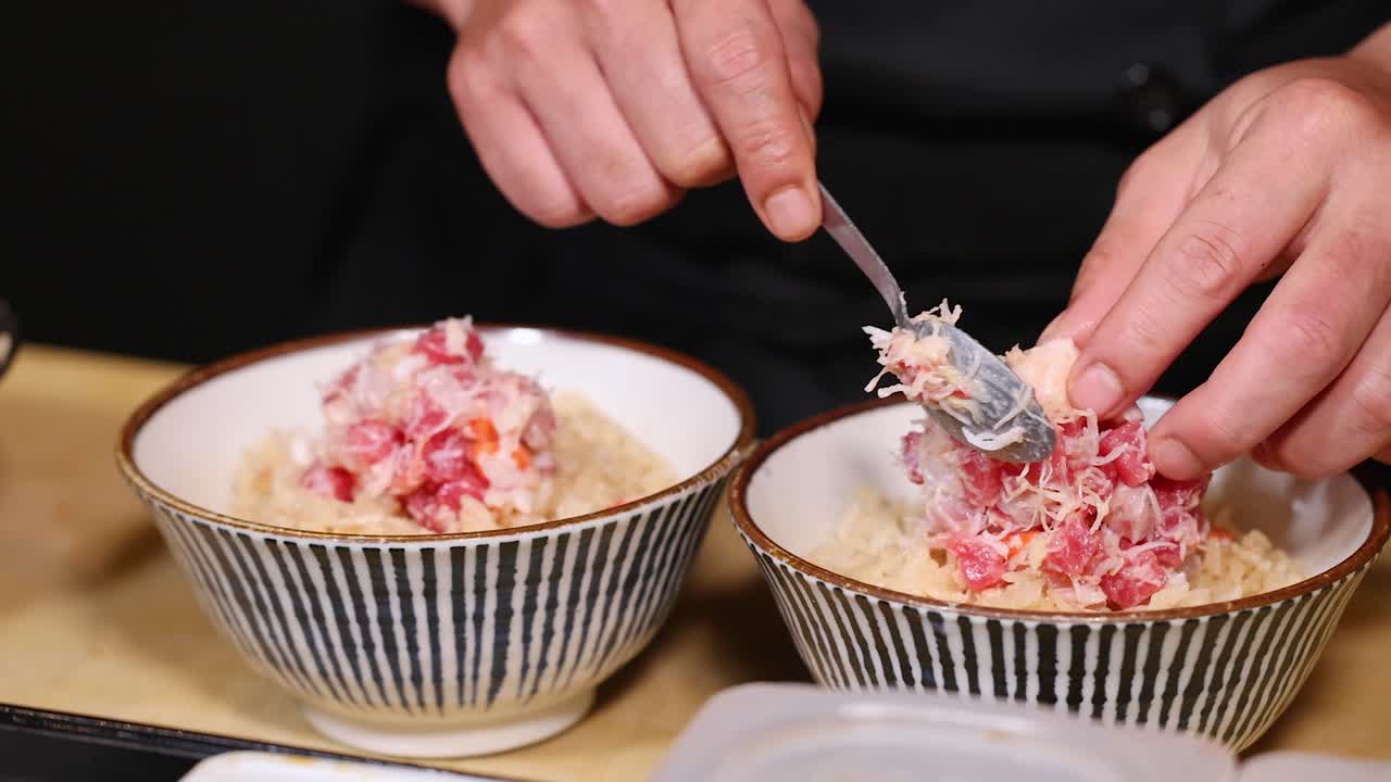 Uno chef dispone con cura polpa di granchio fresca su ciotole di riso in un ambiente di cucina professionale