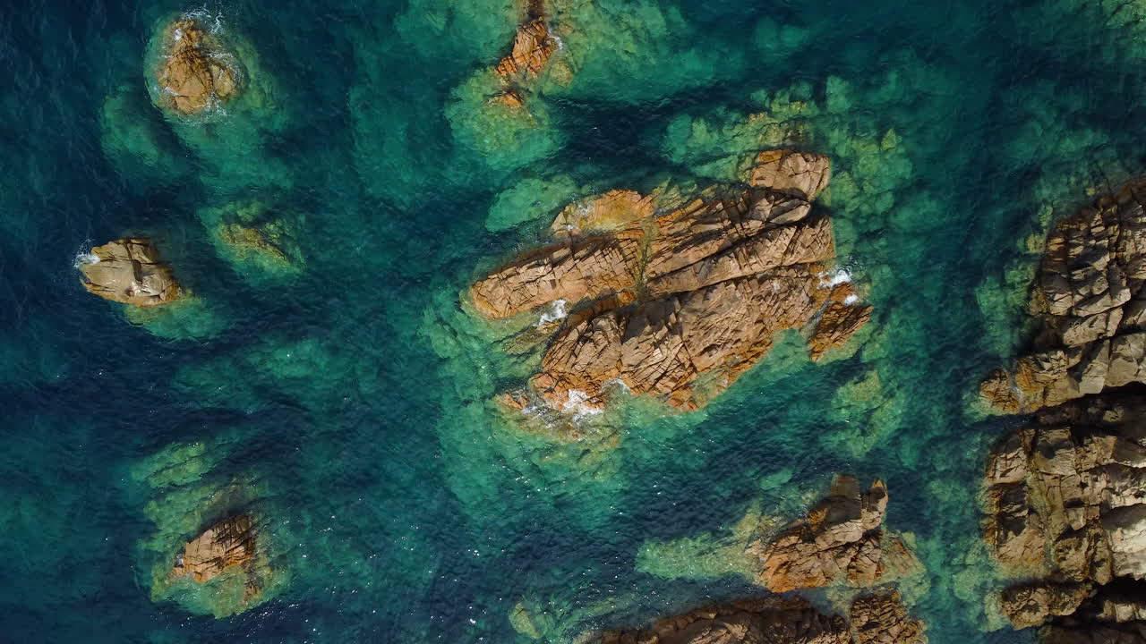Zenithal aerial shot of a rock in crystal-clear turquoise sea, perfect for summer beach holidays, sun, and seaside vacation imagery