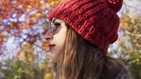 foto de una mujer caucásica con gafas de sol y una gorra roja mirando a su alrededor en un parque en amsterdam