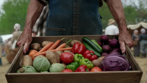 person holding a crate of fresh, colorful vegetables at a market
