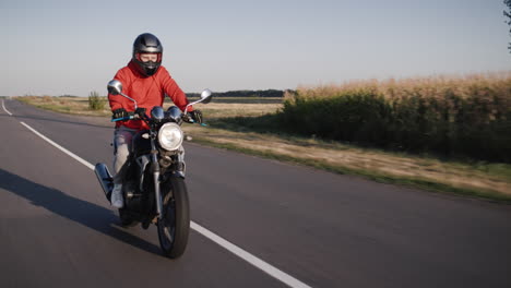 a young man rides a motorbike along corn fields