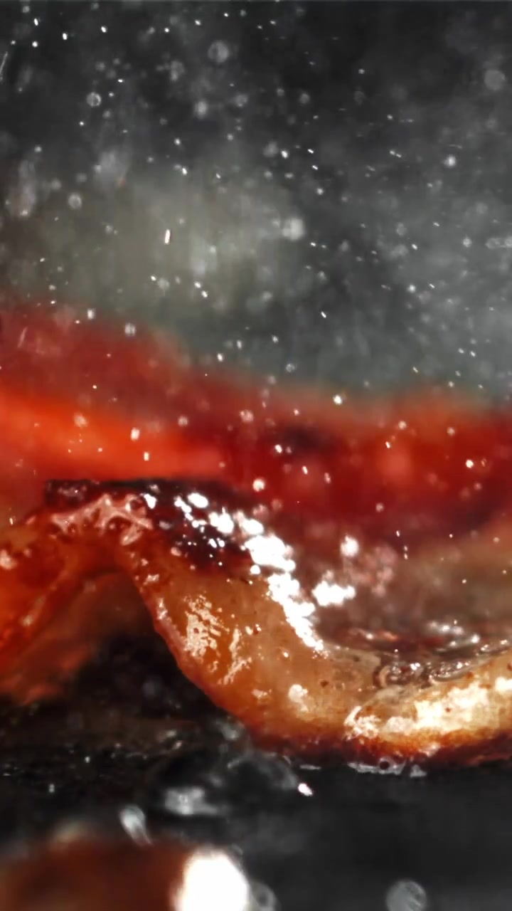 Primo piano di pancetta che frigge e sfrigola in una padella calda