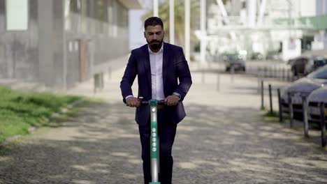 serious businessman riding scooter on street