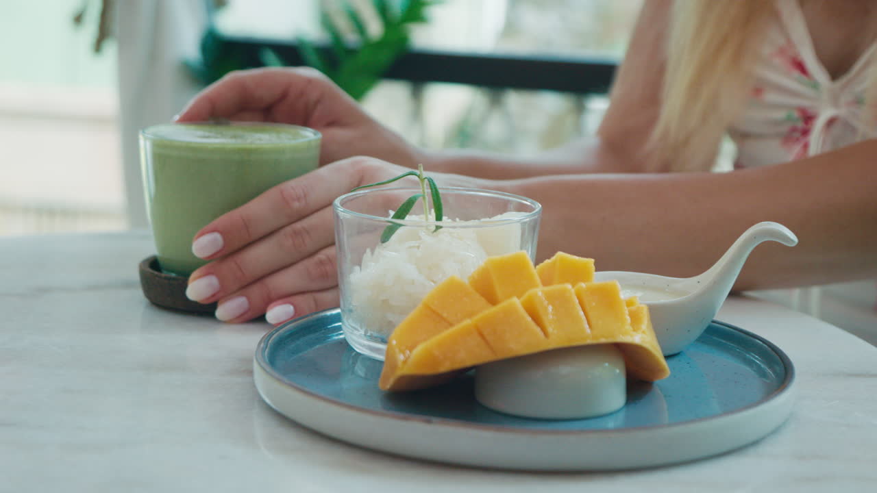 Donna che gusta Mango Sticky Rice e Latte al tè verde