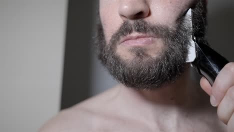 personal care: man carefully trims beard using electric clipper in slo-mo detail