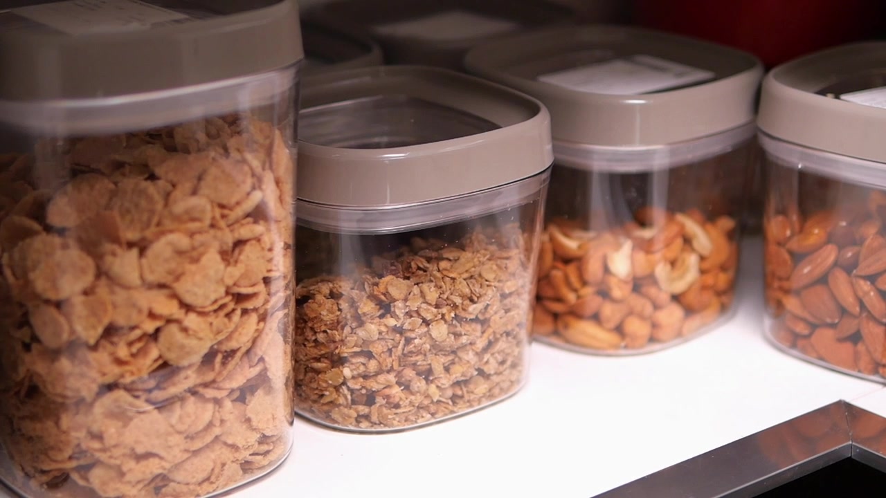Hand Taking a Container of Granola from a Kitchen Pantry Shelf