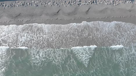 descending birds-eye perspective of ocean waves crashing on the sand then retreating