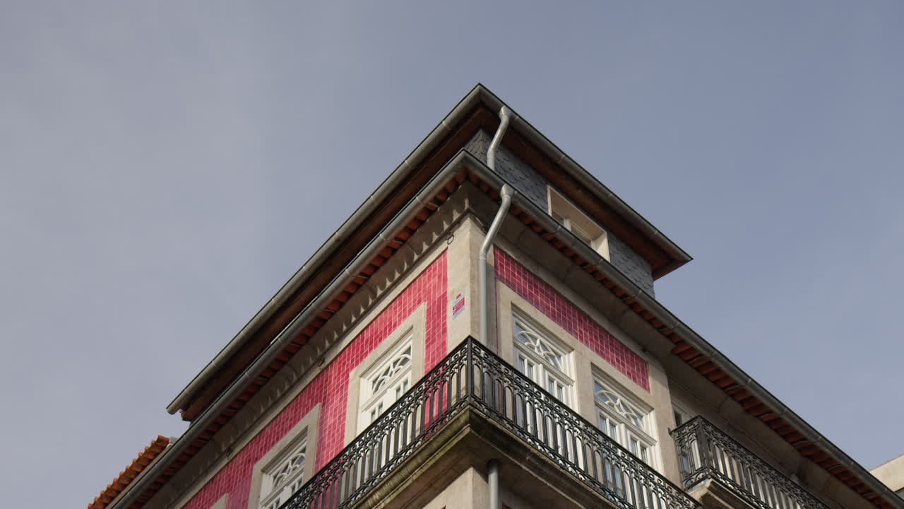 A Building Featuring Traditional Red-tiled Walls, Narrow Wrought-iron Balconies, and Ornate Window Frames in Porto, Portugal - Low Angle Shot