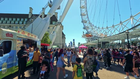 las multitudes disfrutan de helados cerca del london eye.