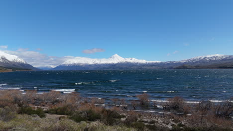 turquoise waves of huechulafquen lake breaking on shore with lanin volcano in background. patagonia, neuquén, argentina