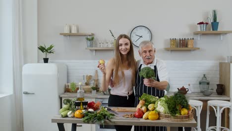 Mature-man-with-grandchild-girl-recommending-eating-raw-vegetable-food.-World-vegan-day-concept