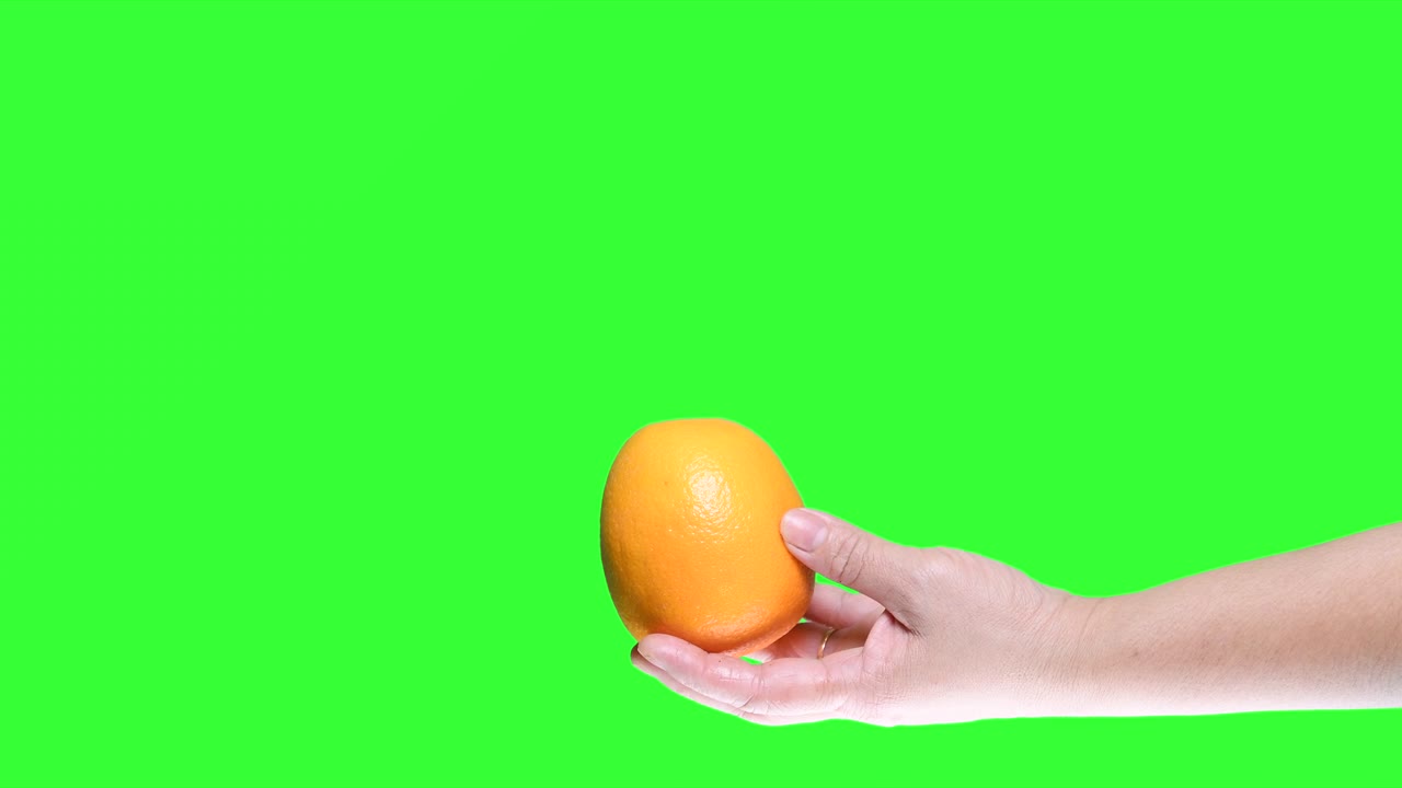 초록색 스크린 배경에 분리 된 오렌지를 들고 있는 손