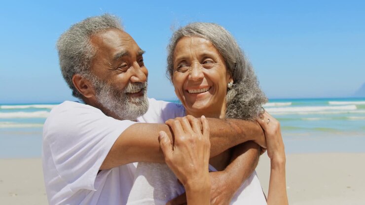 Front view of happy active senior African American man embracing senior woman on the beach 4k