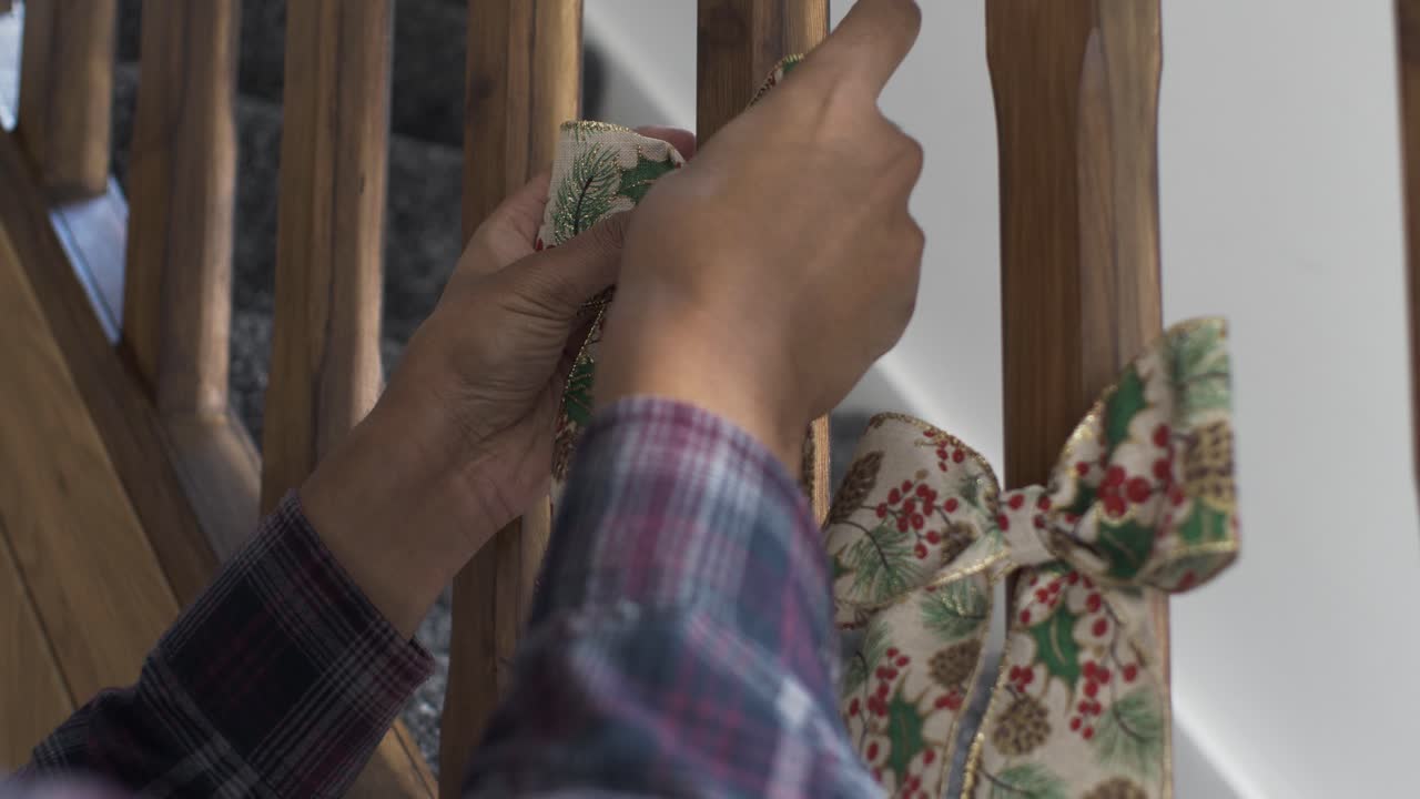 계단 스핀들에 홀리와 겨우살이 디자인으로 이중 크리스마스 활을 배치하는 성인 남성