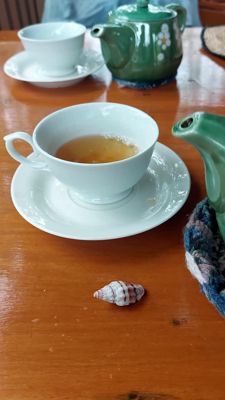 POV of serving tea from a green colored floral design teapot showing a candid mundane moment of daily life of slow living