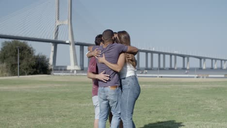 happy people walking in circle and hugging on meadow.