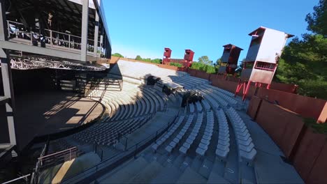 Flying-through-an-open-air-concert,-diving-into-the-crowd-and-soaring-over-a-red-building-in-the-sun