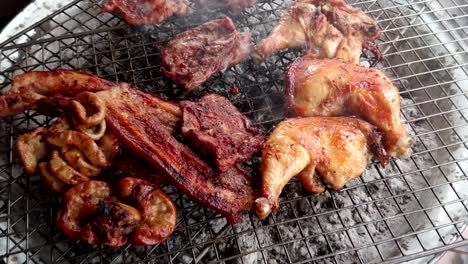 assorted delicious grilled meat over the coals on a barbecue, top view