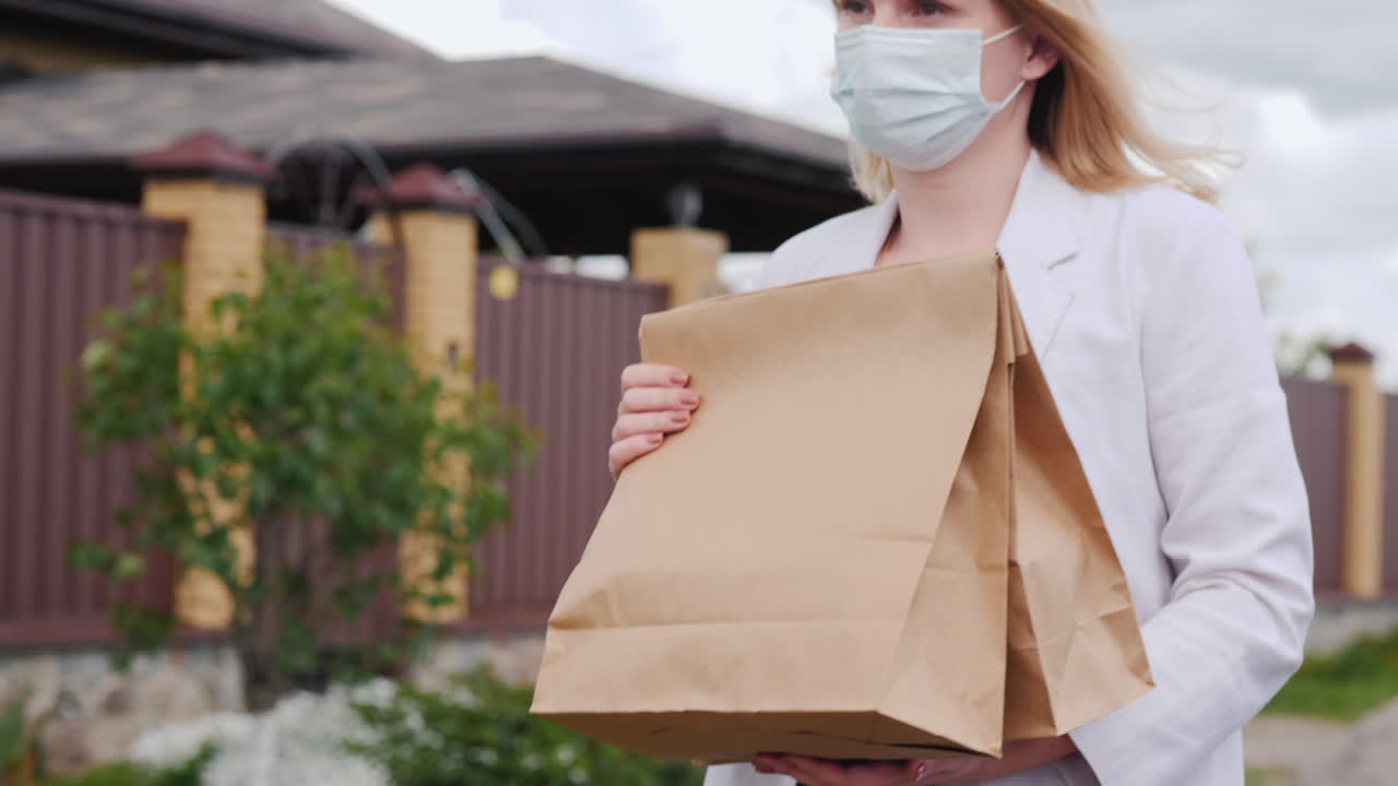 복면을 쓴 여자가 식료품을 집으로 나른다