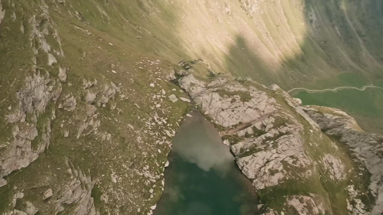 descendiendo rápidamente por encima del majestuoso lago de montaña turquesa, el dron fpv rastrea la encantadora corriente y captura fascinantes cascadas en cautivadoras imágenes aéreas