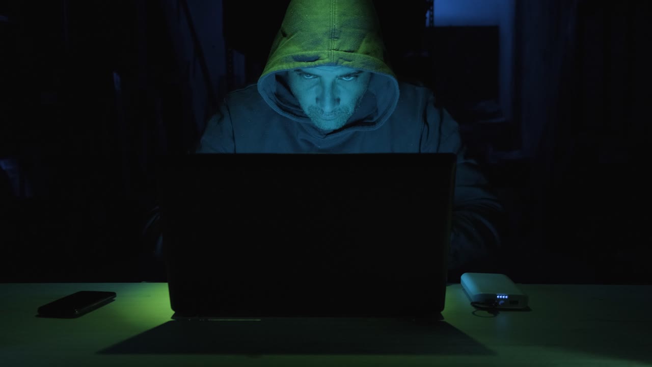 Skilled Male Hacker Working On Laptop Computer At Night In A Dark Room. - close up