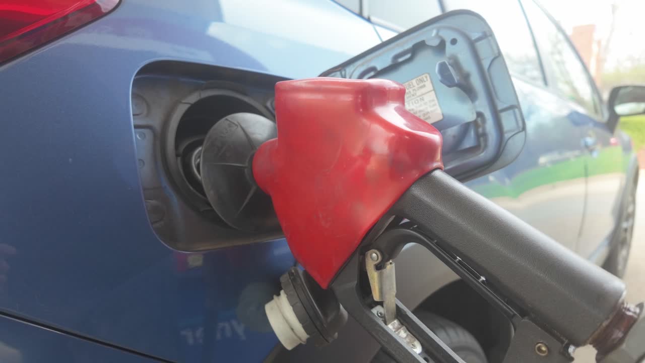 Primo piano di un'auto che fa rifornimento di benzina a una pompa di carburante.