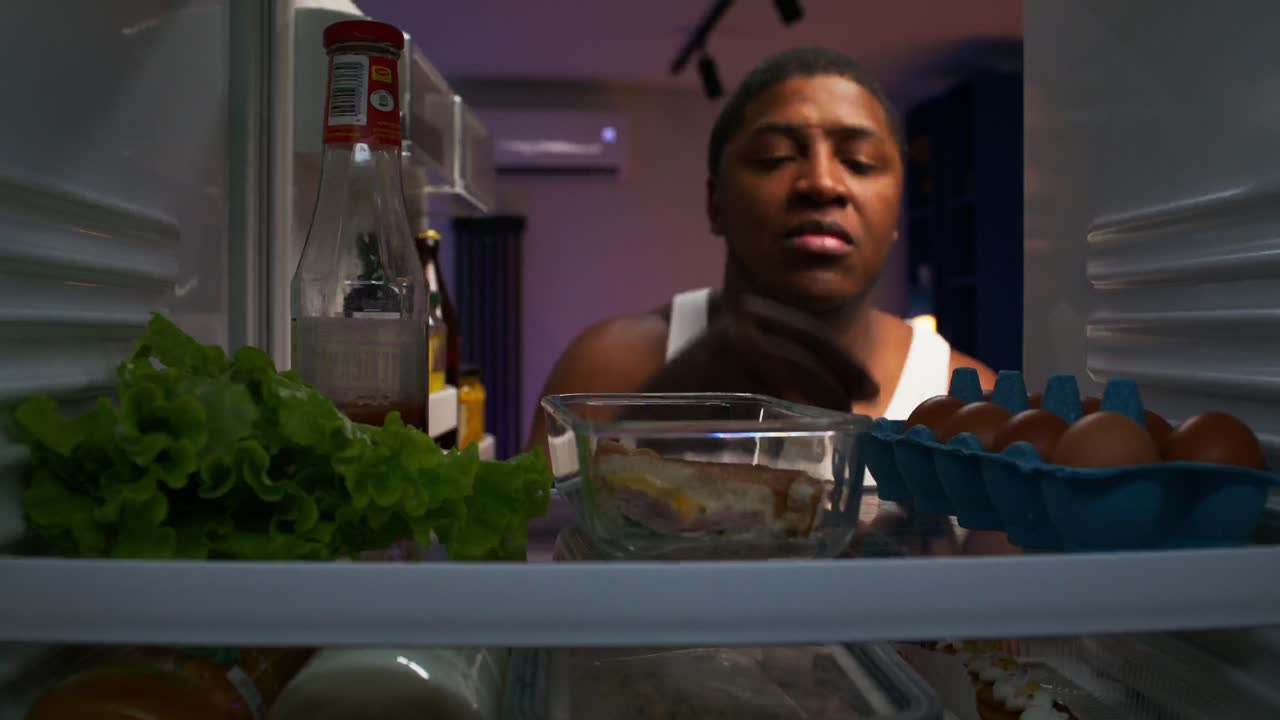 persona que busca comida dentro del refrigerador por la noche