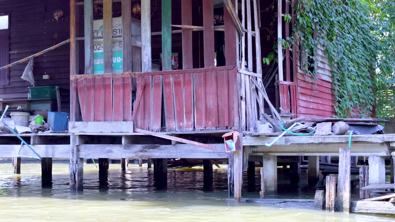 방의 운하를 따라 세련된 목조 집의 조용한 풍경, 전통 건축물과 울창한 초록색을 보여줍니다.