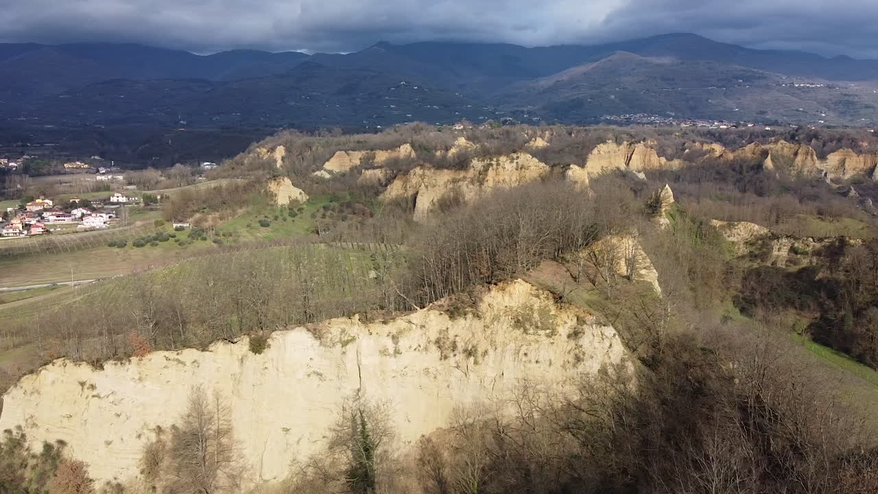 Slow Aerial flying drone shot over prehistoric age canyons Le Balze natural reserve near Reggello. Tuscany, Chianti area. Italy. Winter season, partially sunny sunset.