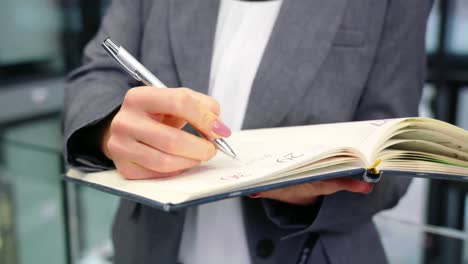 businesswoman writing in diary at office