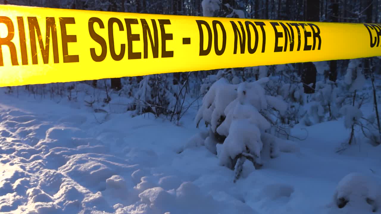 Yellow crime scene tape glowing in winter sunlight over snowy forest ground with footprints, creating a tense forensic investigation mood