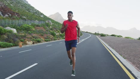 African-american-man-exercising-outdoors-running-on-a-coastal-road