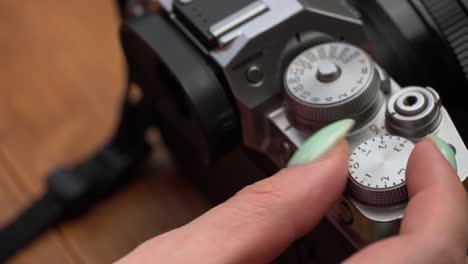 woman's hands twist the aperture wheel on a vintage camera close-up