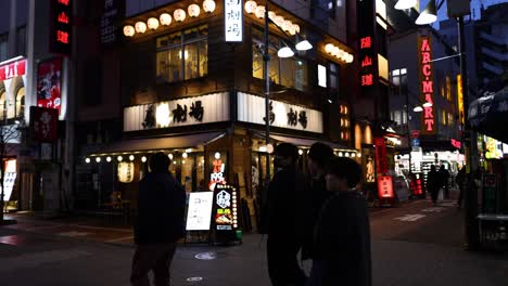 pedestrians walking by illuminated urban buildings