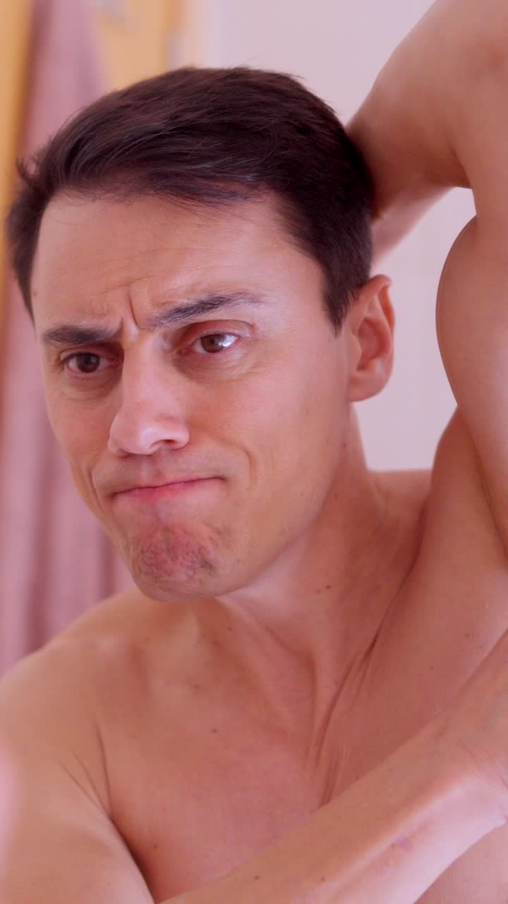 Man putting roll on deodorant on armpit in bathroom