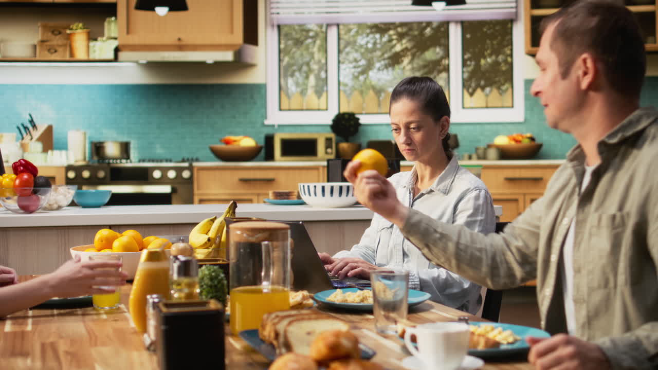 Busy mother ignoring her daughter at breakfast and focusing on her work