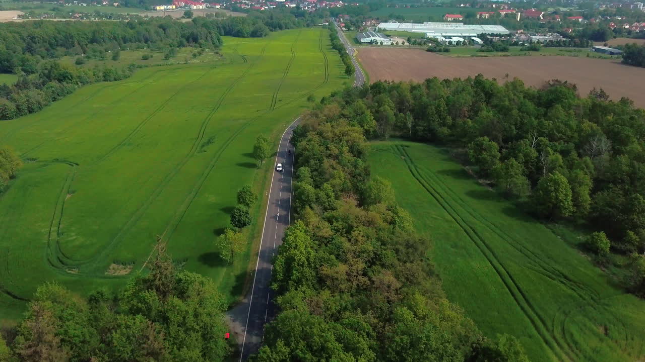 시골 지역의 들판과 숲 사이의 도로에서 운전하는 자동차의 공중 전망