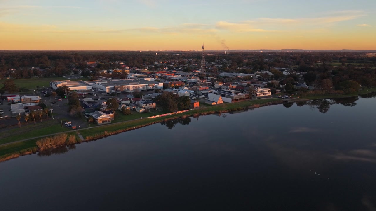 Raymond Terrace sijaitsee leveän Hunter-joen rannalla lämpimässä auringonlaskun valossa, laaja ilmakuva lähestyen.